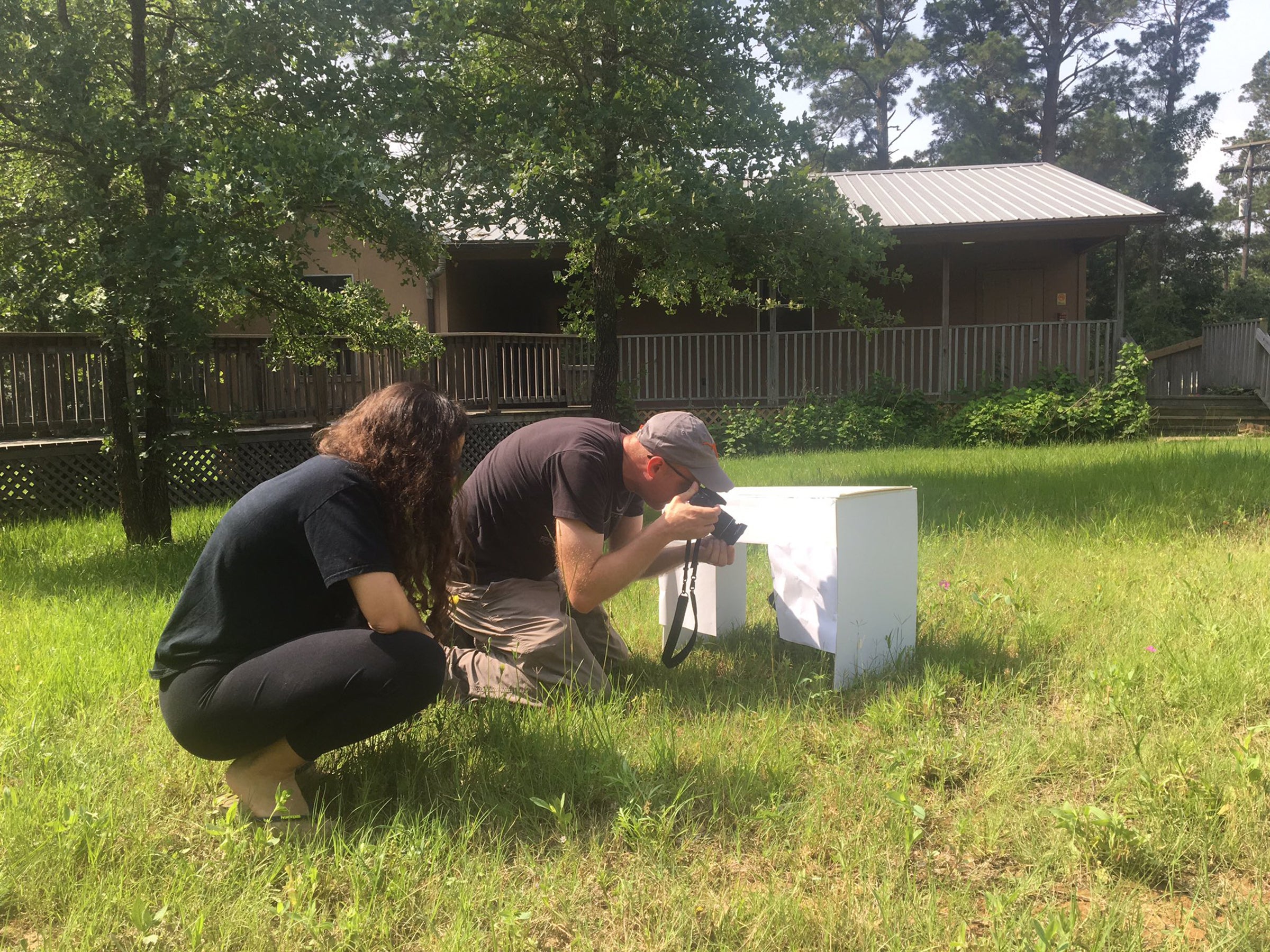 A photo of scientists using photographic equipment outside facilities at the Stengl “Lost Pines” Biological Station